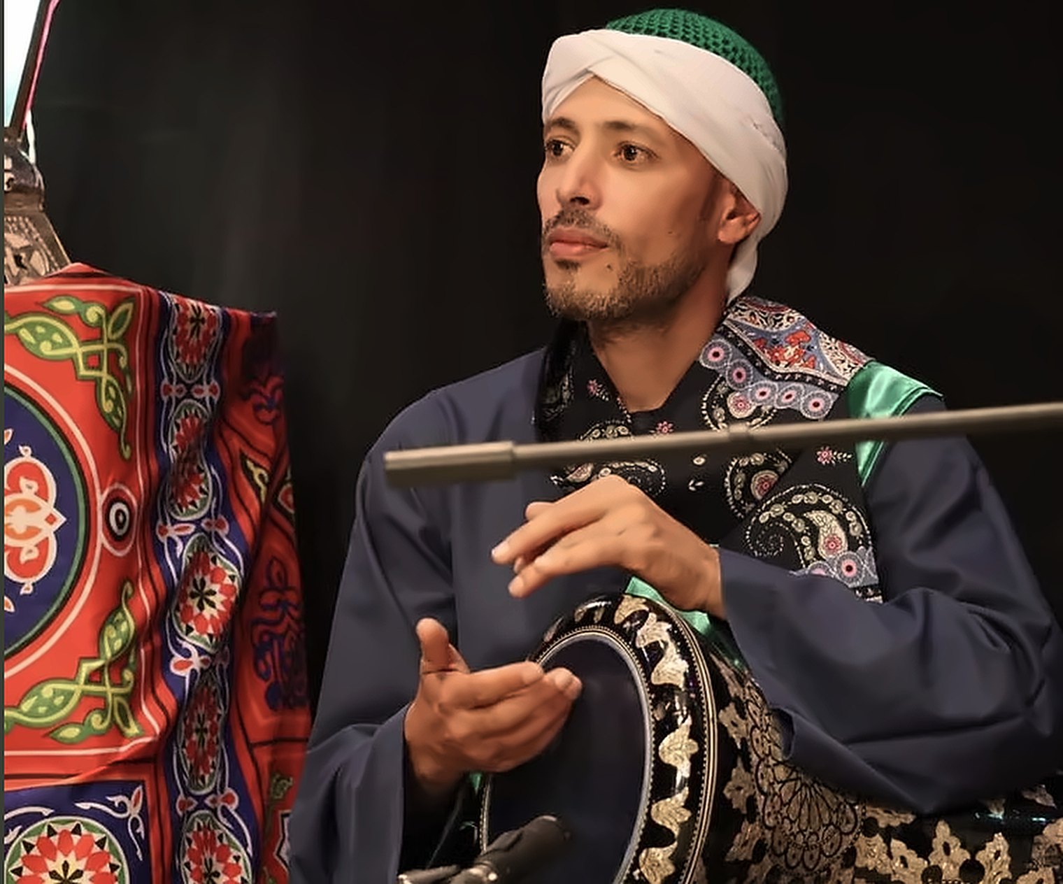 Percussionist in traditional dress playing a frame drum